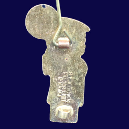 Metallic Golly Badge with a central pin on a dark blue background