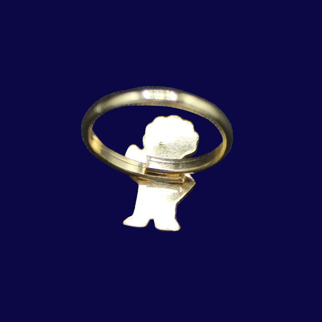 Gold Golly ring with a small angel figure on a dark blue fabric background
