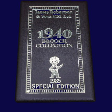 Black leather-bound book titled '1940 Brooch Collection' with engraved text and a Golly brooch illustration on a dark blue background.