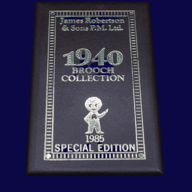 Black leather-bound book titled '1940 Brooch Collection' with engraved text and a Golly brooch illustration on a dark blue background.