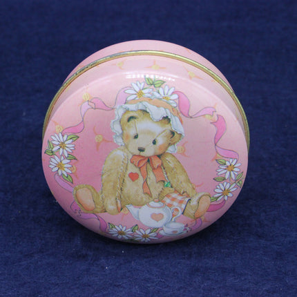 Pink round tin with a teddy bear design on a blue background