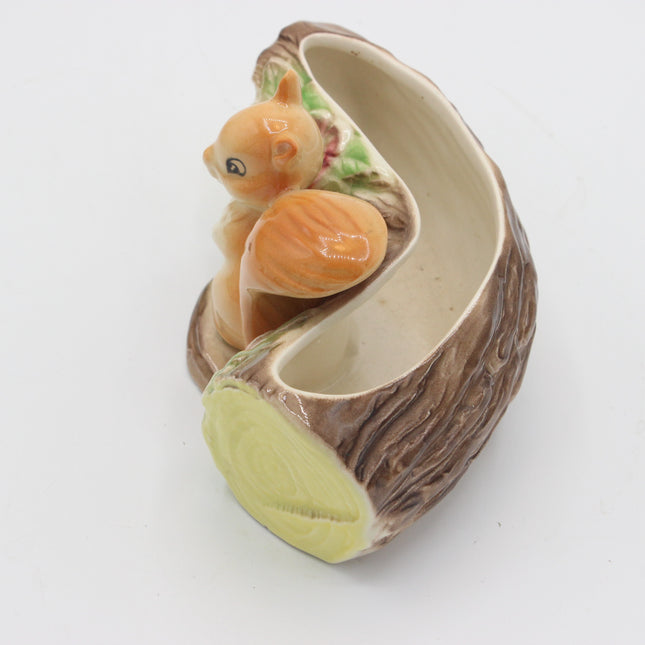 A ceramic decorative bowl shaped like a tree trunk with a small orange squirrel figurine perched inside, photographed on a plain white background.