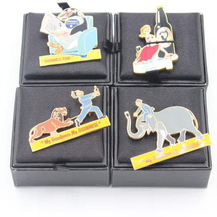 Four enamel pin badges featuring Guinness-themed characters and logos, displayed on a black velvet grid with black presentation boxes.