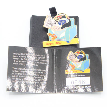 A Guinness-themed enamel pin displayed on top of its black backing card, with an additional back card or insert below showing printed details and a white price sticker. The pin depicts a penguin sitting in a blue armchair with a newspaper and the words 'Guinness' and 'Guinness Time'.