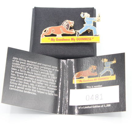 An enamel pin featuring John Gilroy and the lion 'Nile' with the text 'My Goodness My GUINNESS' on a yellow banner, displayed above its black presentation box and an informational card.