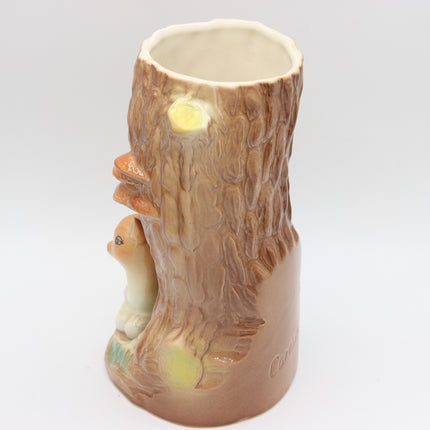 A ceramic mug shaped like a tree stump with a small rabbit carved into the side, shown on a plain light gray background.