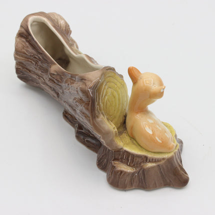A ceramic novelty shoe shaped like a tree stump with a small deer figurine sitting on the base, photographed on a plain white background.