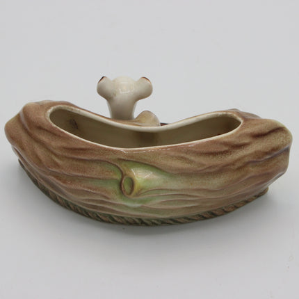 A ceramic planter shaped like a tree trunk with a small bone-shaped accent on top, shown on a plain light gray background.