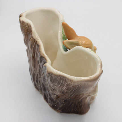 A ceramic planter shaped like a tree trunk with a small painted fox figurine perched on the side, shown on a plain white background.