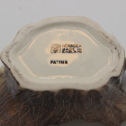Close-up bottom view of a ceramic vessel showing the interior base with Hornsea Made in England and FA'NA markings, plus a mottled brown and cream glazed rim.