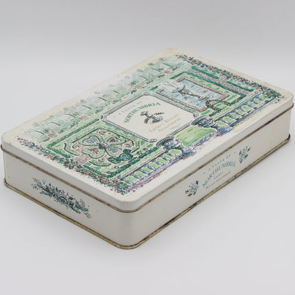A vintage rectangular metal tin box with a white base and an illustrated green garden pavilion design on the lid, photographed on a light gray background.