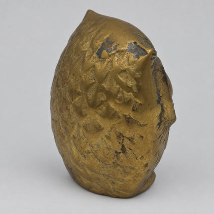 A small metallic owl figurine with a textured, hammered finish in a gold-bronze color, standing upright on a plain light gray background.