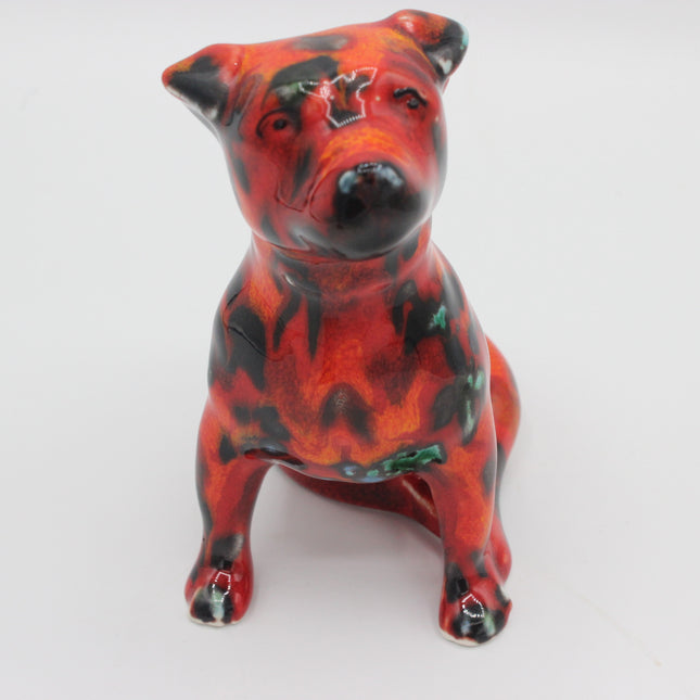 A ceramic figurine of a dog with a glossy red and black marbled pattern, sitting on a plain white background.