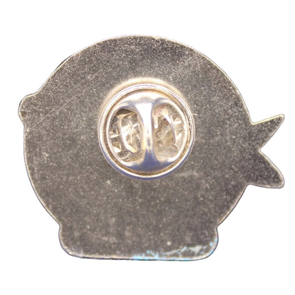 Metallic fish-shaped badge with circular emblem on a blue textured background
