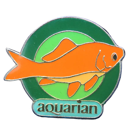 Pin with orange fish design on a green circle against a blue background