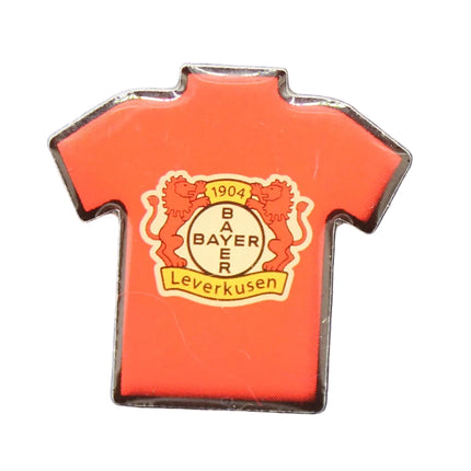 Red shirt-shaped pin with a logo on a blue textured background