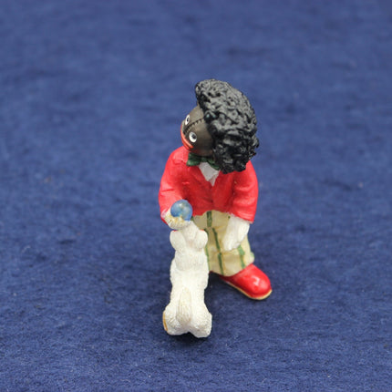 Small figurine of a Golly with a red coat and white shoes on a blue background