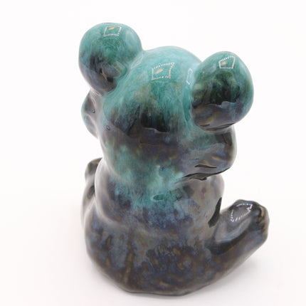 A ceramic figurine of a seated bear, shown from the back, featuring a glossy glaze with a gradient of teal, dark blue, and black, accented with small white geometric patterns on its ears.