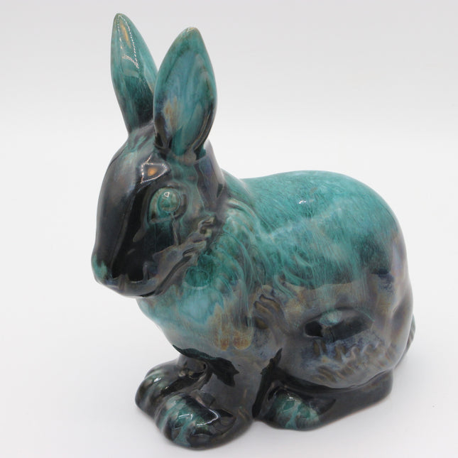 A ceramic rabbit figurine with a glossy glaze featuring teal, turquoise, and black tones, photographed against a plain white background.