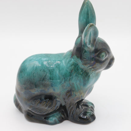 A glossy ceramic rabbit figurine with a mottled turquoise, teal, and dark charcoal glaze, shown against a plain white background.