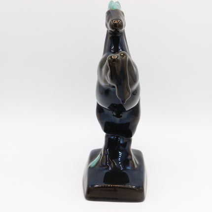 A glossy ceramic figurine of three stacked geese in a dark navy blue glaze with small turquoise accents on the beaks and backs, set against a plain white background.