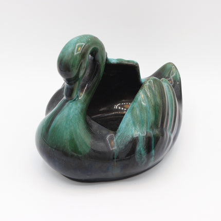 A ceramic swan-shaped planter with a glossy glaze in shades of green and black, photographed on a seamless white background.