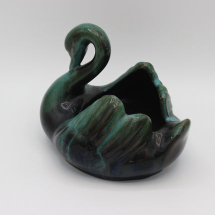 A sculptural ceramic planter shaped like a swan, featuring a glossy glaze with a gradient of deep forest green, teal, and black.