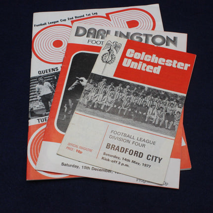 Two vintage football match programs from Darlington and Colchester United on a dark background