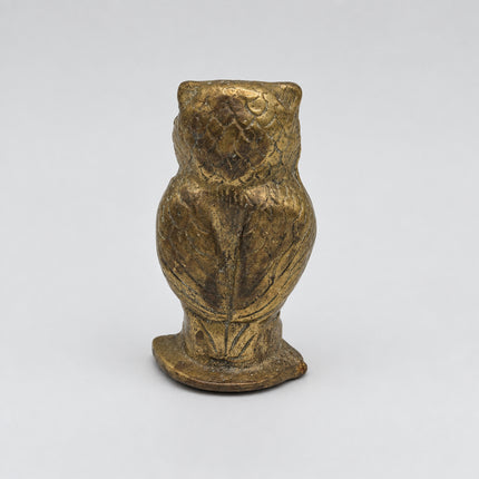 A small owl figurine made of textured metal, likely bronze or brass, shown from the back against a plain white background.
