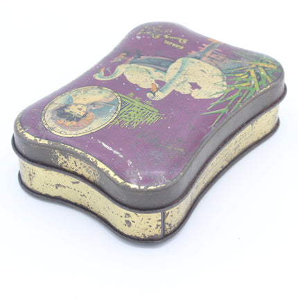 A vintage rectangular metal tin with rounded corners, featuring a purple illustrated lid and a distressed gold-toned base, photographed on a white background.