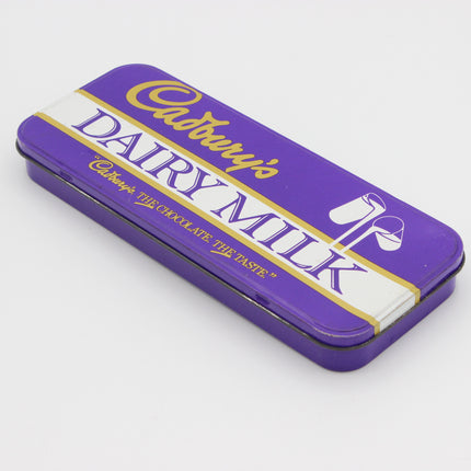 A purple Cadbury's Dairy Milk chocolate tin with white and gold lettering, photographed on a clean white background.
