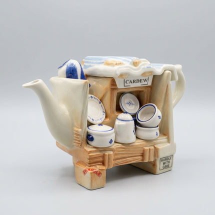 A ceramic Cardeau teapot-shaped storage box filled with small blue-and-white porcelain cups, saucers, and lids, photographed on a plain white studio background.