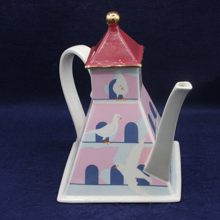 Decorative teapot with a bird house design on a dark blue background