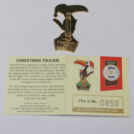 Gold Christmas Toucan figurine with a card detailing its history on a white background