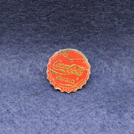 Coca-Cola bottle cap enamel pin badge on a textured blue background