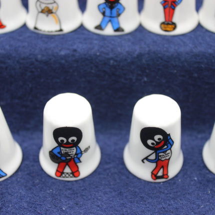 Set of white thimbles with Golly designs on a blue fabric background