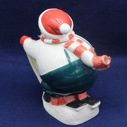 Coronation Ware Sled Teapot with a red hat and green coat on a blue background