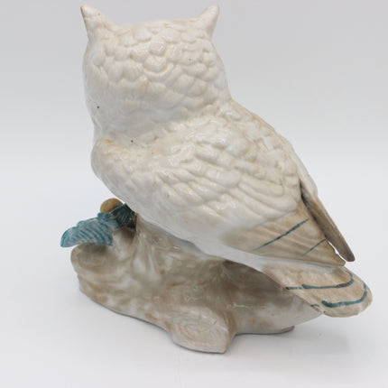 A ceramic owl figurine perched on a branch, shown from the back against a plain white studio background.