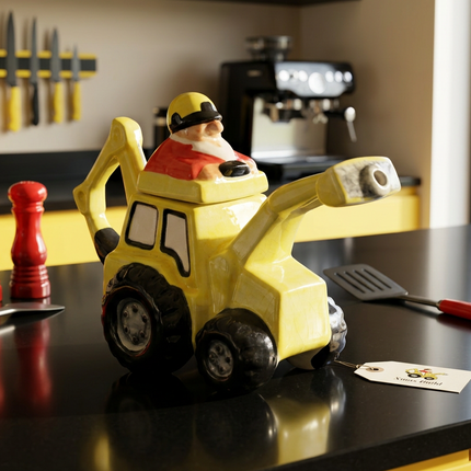 A yellow construction truck-shaped ceramic teapot, displayed on a black countertop in a kitchen setting.