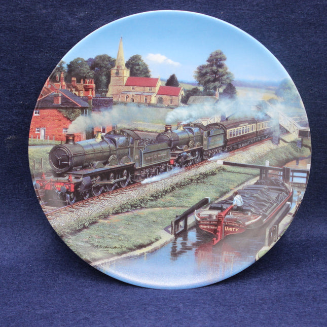 Decorative plate with a steam train and village scene on a blue background