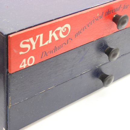 Close-up of Dewhurst’s Sylko 40 lettering on the red top drawer of a vintage thread cabinet.