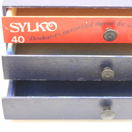 Vintage Dewhurst’s Sylko three-drawer thread cabinet with dark-painted fronts and round knobs.