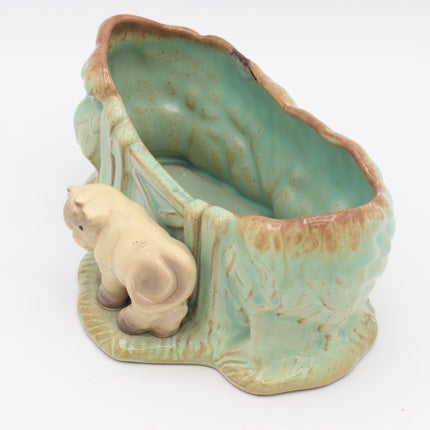 A vintage ceramic animal-shaped planter or bowl featuring a small beige piglet standing beside an irregularly shaped interior. The piece has a glossy light green and turquoise glaze with brown distressed edging, set against a plain white background.