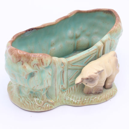 A vintage ceramic nursery planter shaped like a barn with a small beige sheep figurine, featuring a glossy turquoise and brown glaze on a white background.
