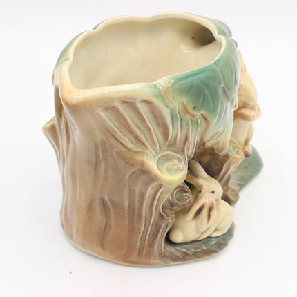 A ceramic rabbit-shaped planter shaped like a tree stump, featuring a beige and brown textured body with green glazed accents, set against a plain white background.