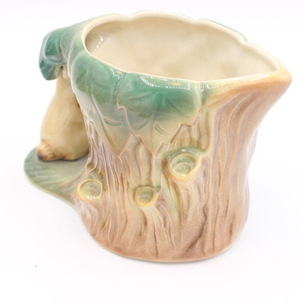 A ceramic tree stump planter with a glazed finish, featuring a green leafy top rim and a beige textured bark base on a white background.