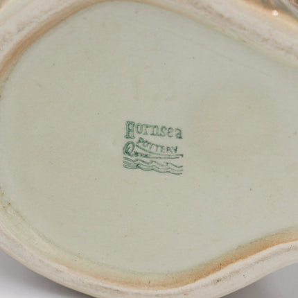 Close-up of the interior base of a ceramic object, showing a pale green glaze and a green printed mark reading 'Hornsea Pottery' on a white background.