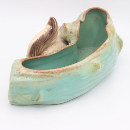 A ceramic planter shaped like a stylized shell or leaf, featuring a glossy light green glazed interior and exterior with a rustic brown unglazed edge, shown on a white background.