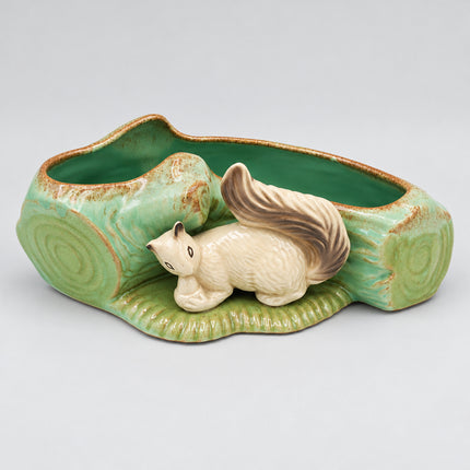 A ceramic planter shaped like a tree stump with a small beige squirrel figurine in the center, featuring a glossy light green and brown glaze on a white background.