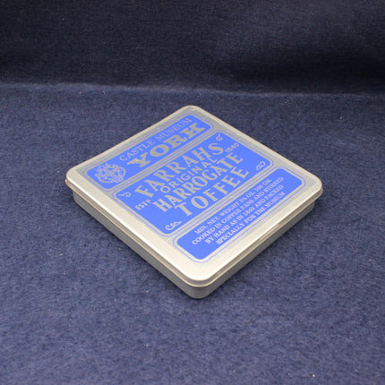 Box of Harrogate Toffee with blue label on a dark blue fabric background